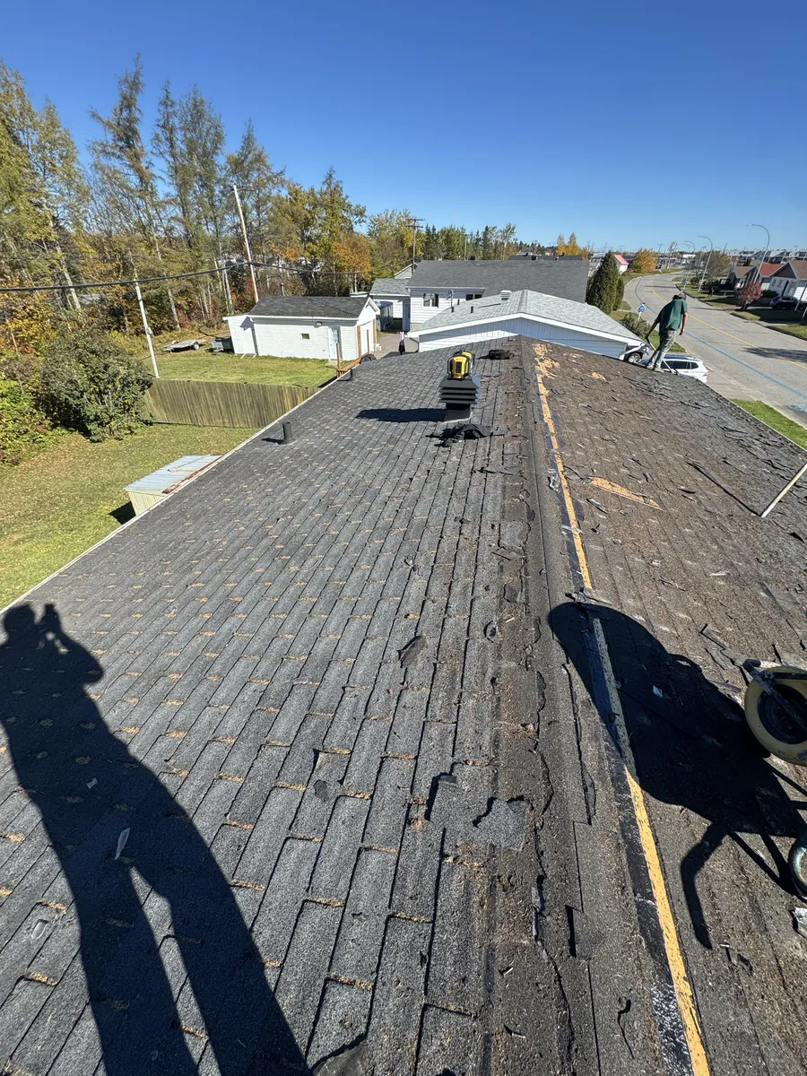 Toit en cours de dépose à Port-Cartier : une partie de l'ancienne couverture est retirée et le support du toit est visible.